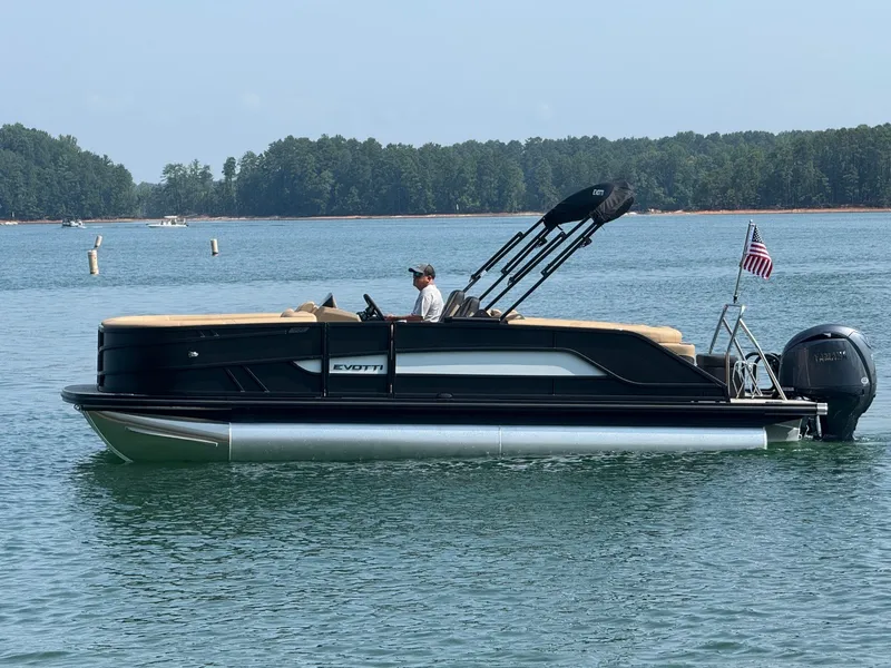 Slide: The Image of A 2027 Evotti 521QL pontoon boat on a calm lake with a driver on board. - 6