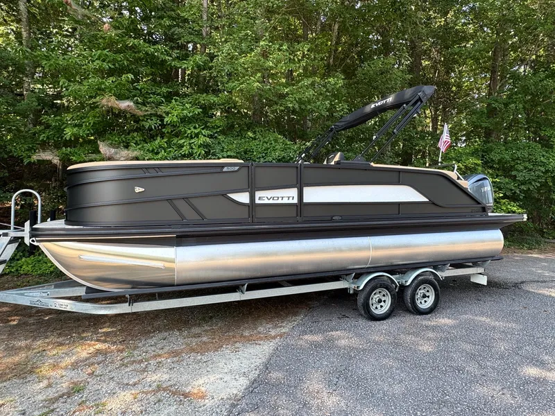 Slide: The Image of A 2027 Evotti 521QL pontoon boat on a trailer, surrounded by trees. - 7