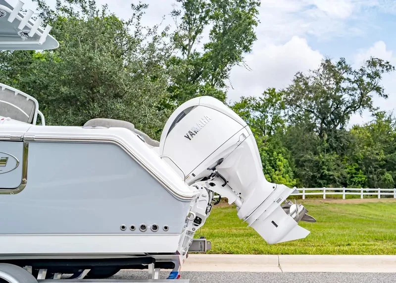 Slide: The Image of A Sea Hunt Ultra 265 SE boat with a Yamaha outboard motor, parked on a road beside trees. - 5
