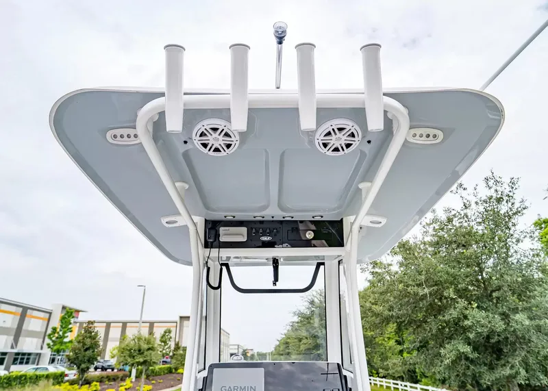 Slide: The Image of The image shows the T-top of a Sea Hunt Ultra 245 SE boat with speakers and rod holders. - 14