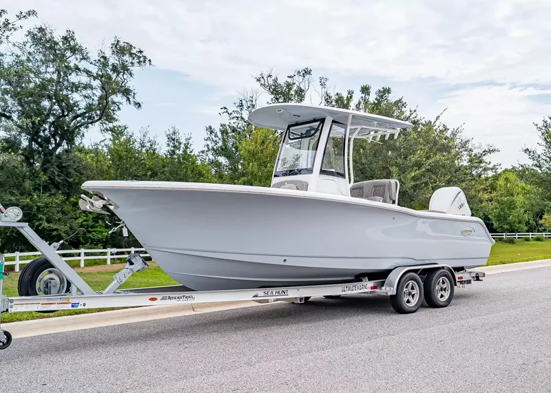 The Image of A 2027 Sea Hunt Ultra 245 SE boat on a trailer, surrounded by trees. - 1