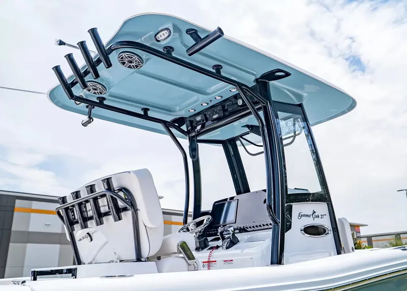 Slide: The Image of The image shows the helm of a Sea Hunt Gamefish 27 Coffin Box boat. It features a modern design with a blue top and multiple fishing rod holders. - 5
