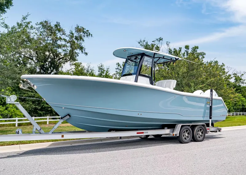The Image of A 2027 Sea Hunt Gamefish 27 Coffin Box boat on a trailer, surrounded by trees. - 1