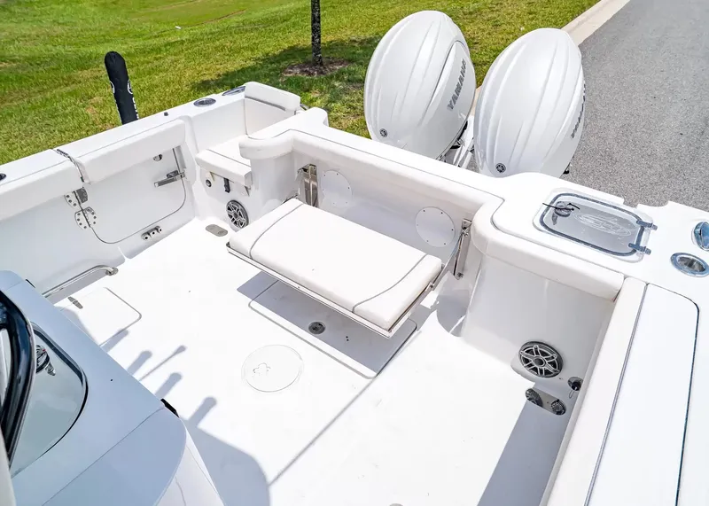 Slide: The Image of The image shows the cockpit of a Sea Hunt Gamefish 27 Coffin Box boat. It features a white cushioned bench and two outboard motors. - 10