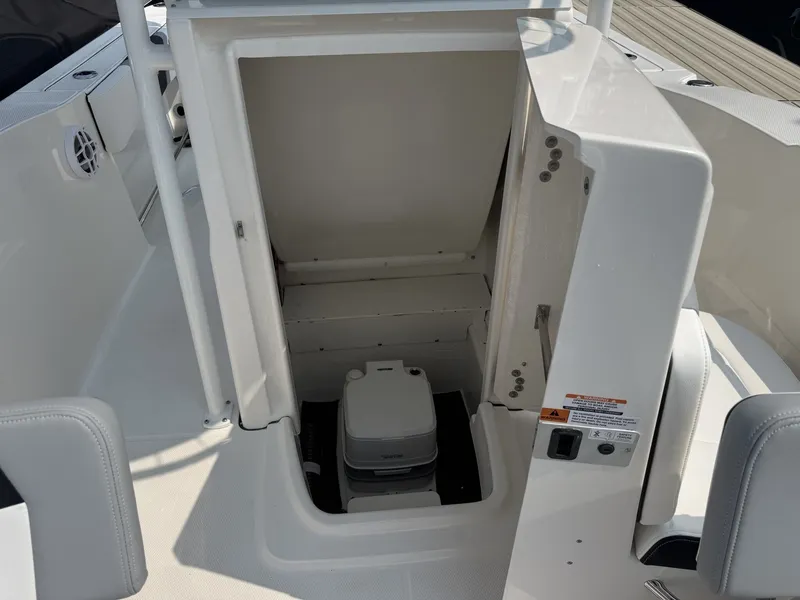 Slide: The Image of The image shows a white boat toilet in an open storage compartment on a Robalo R200 Center Console boat. - 6