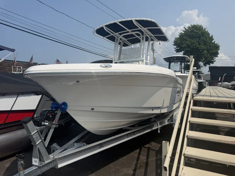 The Image of A 2027 Robalo R200 Center Console boat on a trailer next to a wooden dock. - 1
