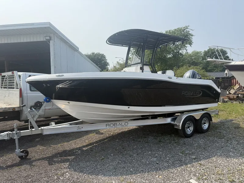 The Image of A 2027 Robalo R200 Center Console boat on a trailer beside a building. - 1