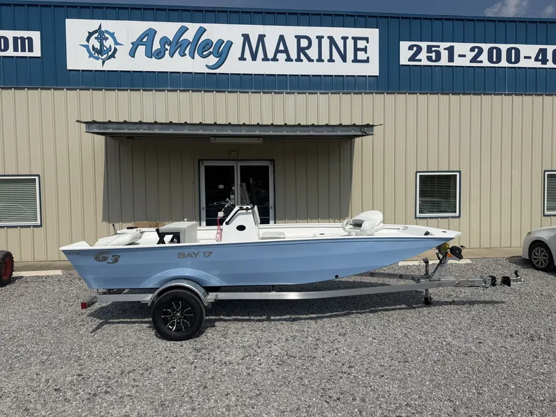 The Image of A white G3 Bay 17 boat on an aluminum trailer in front of a building with "Ashley Marine" signage. - 1