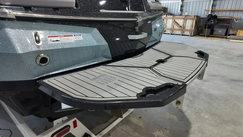 Slide: The Image of The image shows the rear of a 2024 MasterCraft XStarS with a gray swim platform. - 13