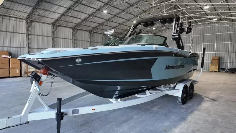 Slide: The Image of A 2024 MasterCraft XStarS boat on a trailer inside a large warehouse. - 17