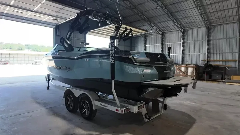 Slide: The Image of A 2024 MasterCraft XStarS boat on a trailer inside a large warehouse. - 15