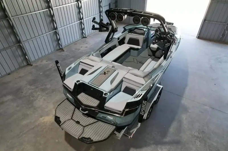 Slide: The Image of A modern 2024 MasterCraft XStarS in a warehouse. The boat features sleek design with gray upholstery and a sturdy tower. - 6