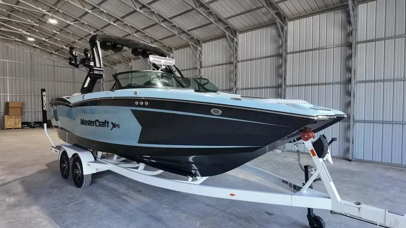 Slide: The Image of A 2024 MasterCraft XStarS boat on a trailer inside a warehouse. - 21