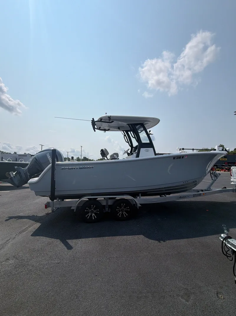 The Image of A 2025 Sportsman Open 232 Center Console boat on a trailer under a sunny sky. - 1