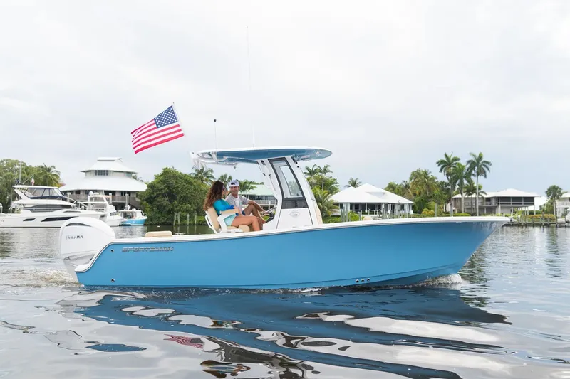Slide: The Image of A blue 2025 Sportsman Open 232 Center Console boat on calm water, with a woman steering. - 17