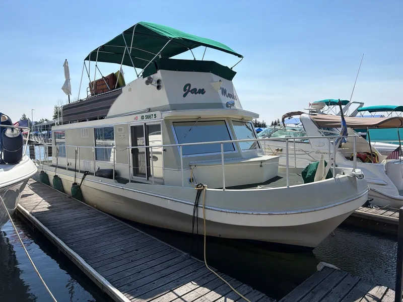 The Image of A 1977 Cruise-A-Home 40 houseboat docked. It features a green canopy. - 1