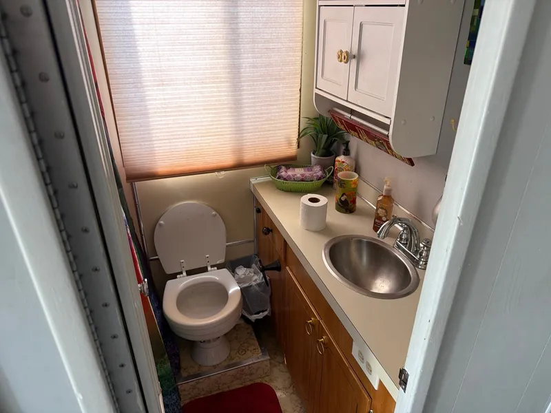Slide: The Image of The image shows a small boat bathroom with a toilet, sink, and storage space. - 9
