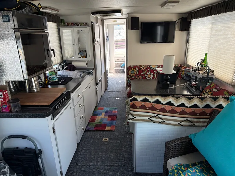 Slide: The Image of Interior of a 1977 Cruise-A-Home 40 with kitchen, seating area, and TV. - 13