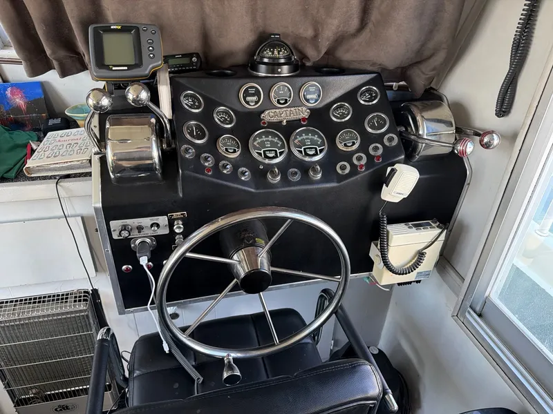 Slide: The Image of The image shows the helm of a 1977 Cruise-A-Home 40 boat with various instruments and a steering wheel. - 12