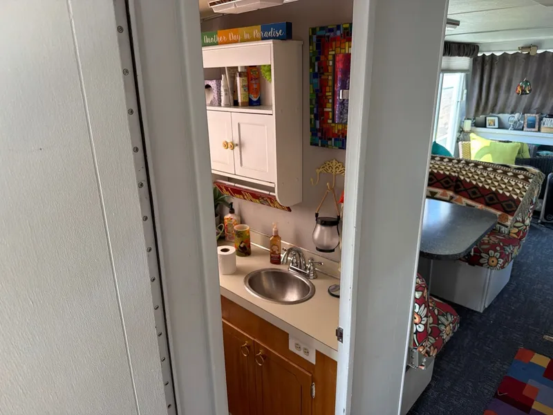 Slide: The Image of Interior view of a 1977 Cruise-A-Home 40 with a small kitchen, sink, and colorful decorations. - 8