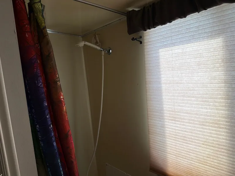 Slide: The Image of A shower area with a colorful curtain and a window with a blind. - 10