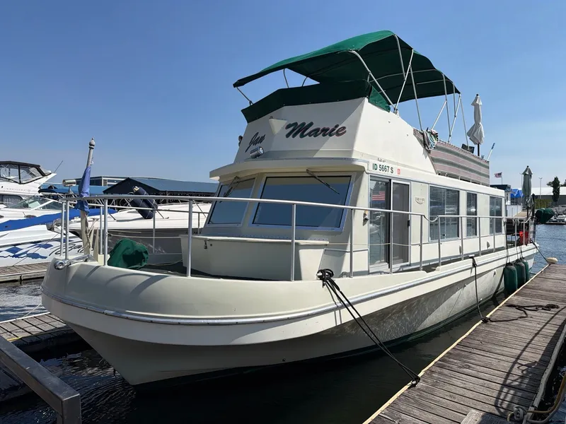 Slide: The Image of A 1977 Cruise-A-Home 40 houseboat docked. It features a green canopy and spacious cabin. - 3