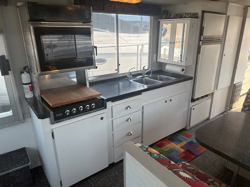 Slide: The Image of The kitchen of a 1977 Cruise-A-Home Corsair 40 with stove, sink, and cabinets. - 24