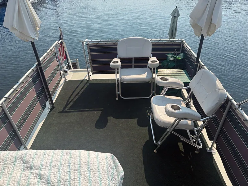 Slide: The Image of The deck of a 1977 Cruise-A-Home Corsair 40 with white chairs and umbrellas by the water. - 10