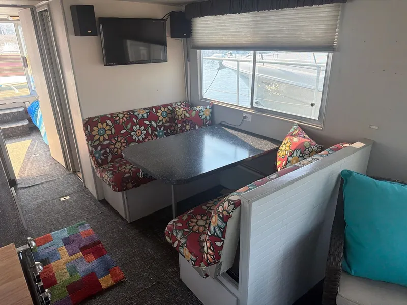 Slide: The Image of Interior of a 1977 Cruise-A-Home Corsair 40 with colorful seat cushions and a table. - 23