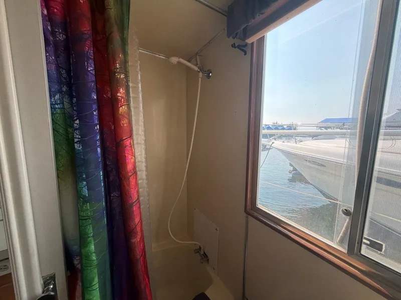 Slide: The Image of The shower in a boat with a colorful curtain and a window overlooking the water. - 21