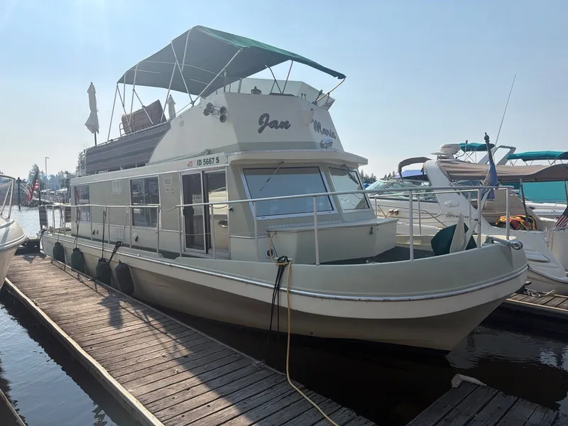 Slide: The Image of A 1977 Cruise-A-Home Corsair 40 houseboat docked. It features a green canopy. - 2