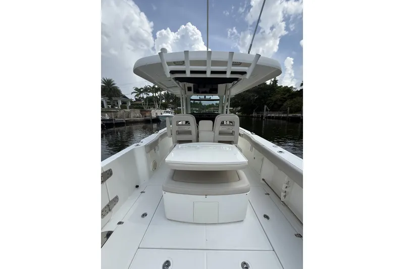 Slide: The Image of 2016 Boston Whaler 330 Outrage boat interior with seating and table, under a cloudy sky. - 25