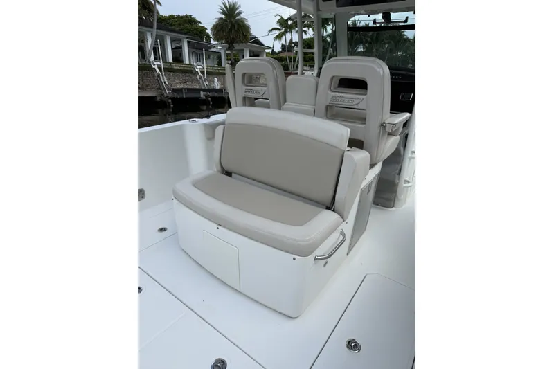 Slide: The Image of 2016 Boston Whaler 330 Outrage boat seating area with cushioned seats and storage. - 26