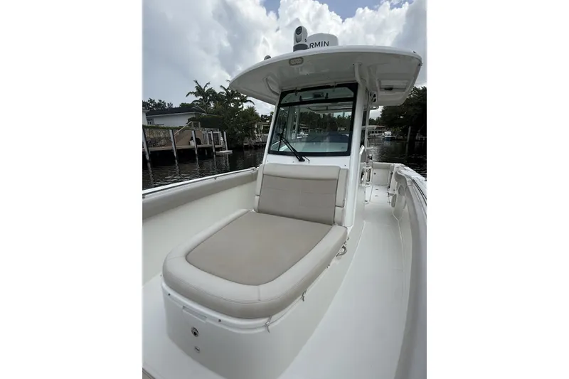 Slide: The Image of 2016 Boston Whaler 330 Outrage boat with cushioned seating, docked near waterfront homes. - 16
