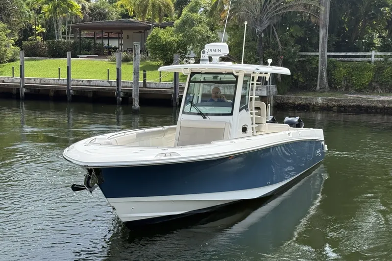 Slide: The Image of 2016 Boston Whaler 330 Outrage boat cruising on a calm waterway near a dock. - 2