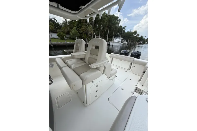 Slide: The Image of 2016 Boston Whaler 330 Outrage boat interior with cushioned seating and scenic waterfront view. - 18
