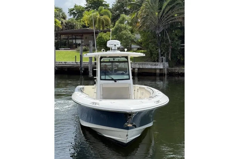 Slide: The Image of 2016 Boston Whaler 330 Outrage boat on calm water, surrounded by lush greenery. - 3