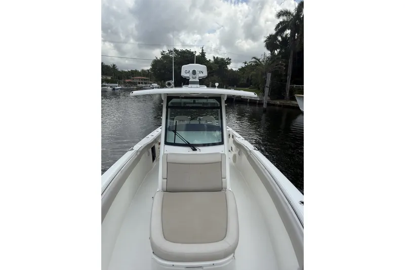Slide: The Image of 2016 Boston Whaler 330 Outrage boat on calm water, featuring a spacious deck and seating. - 12