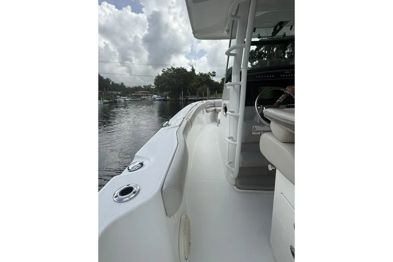 Slide: The Image of 2016 Boston Whaler 330 Outrage boat interior with seating and steering wheel, docked by a calm waterway. - 27