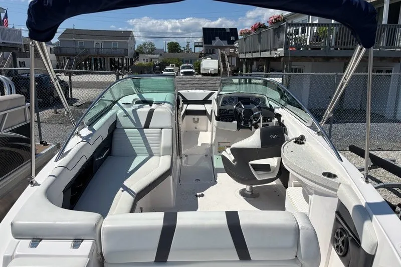 Slide: The Image of 2016 Regal 24 FasDeck boat interior with seating and steering wheel, docked outdoors. - 15
