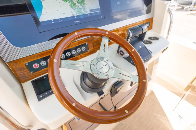 Slide: The Image of Steering wheel and dashboard of 2023 Chris-Craft Catalina 30 boat, featuring modern navigation displays. - 33