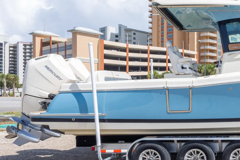 Slide: The Image of 2023 Chris-Craft Catalina 30 boat with Mercury engines on a trailer, urban backdrop. - 23