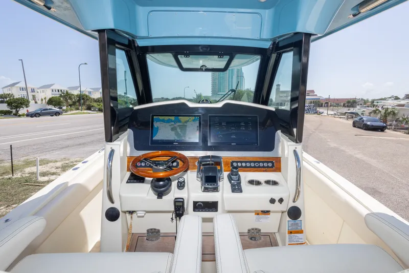 Slide: The Image of 2023 Chris-Craft Catalina 30 helm with navigation screens and controls, parked near a coastal road. - 29