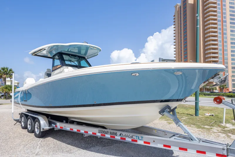 Slide: The Image of 2023 Chris-Craft Catalina 30 boat on trailer, parked near tall buildings under clear blue sky. - 9