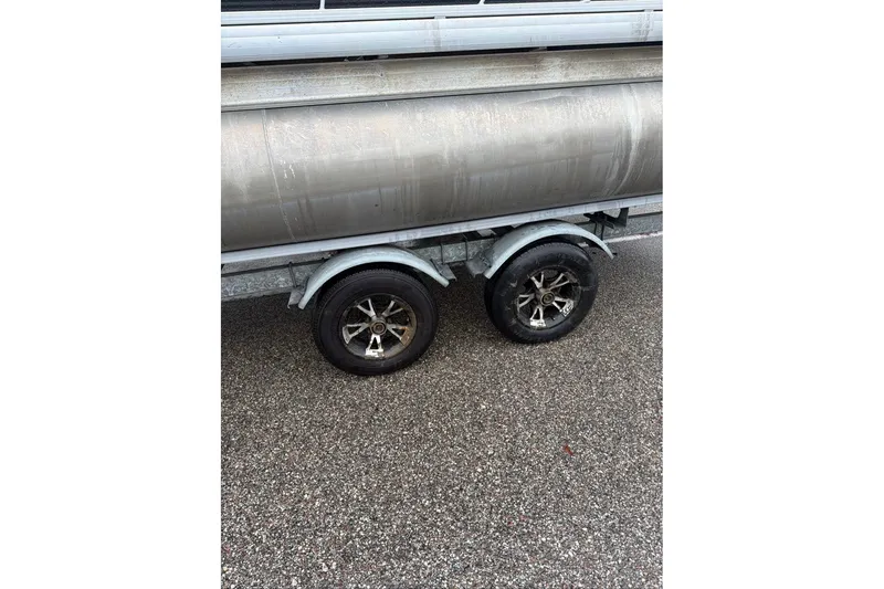 Slide: The Image of Trailer wheels of a 2016 Godfrey Sweetwater 2286 pontoon boat on wet pavement. - 2