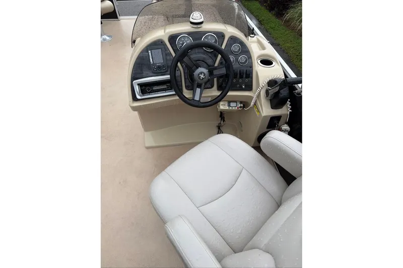 Slide: The Image of Captain's seat and helm of 2016 Godfrey Sweetwater 2286 boat, featuring steering wheel and controls. - 12