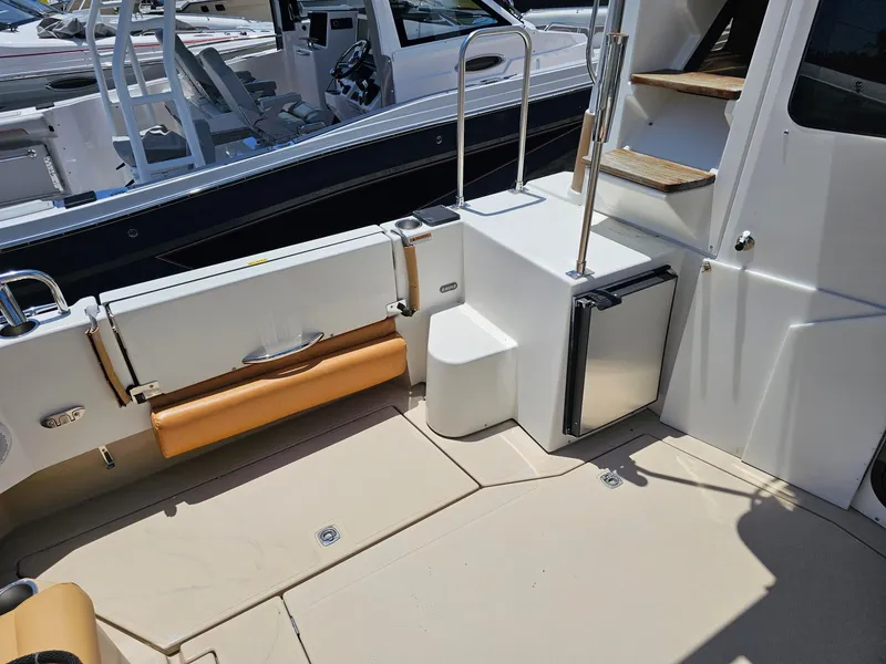 Slide: The Image of The image shows the cockpit of a 2014 Ranger Tugs 31-CB with seating area and refrigerator. - 19