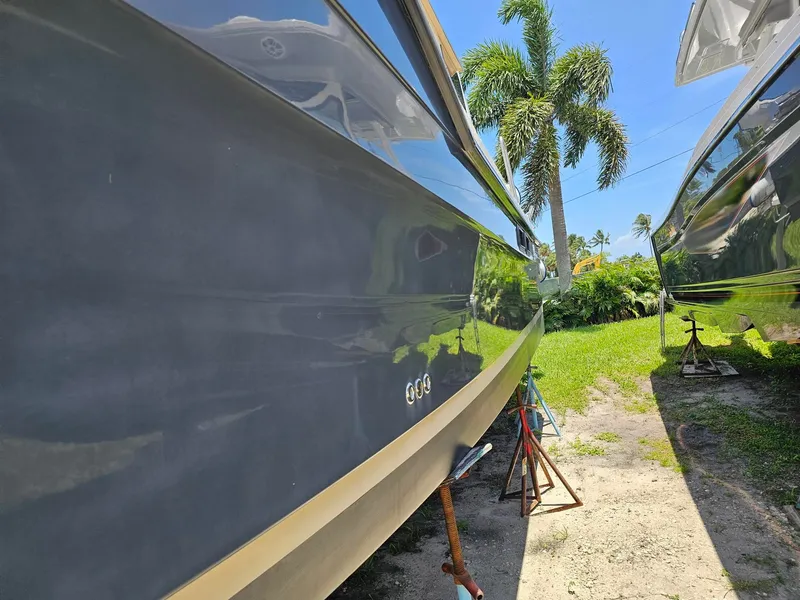 Slide: The Image of Side view of a 2014 Ranger Tugs 31-CB, propped on a sunny lawn with palm trees. - 6