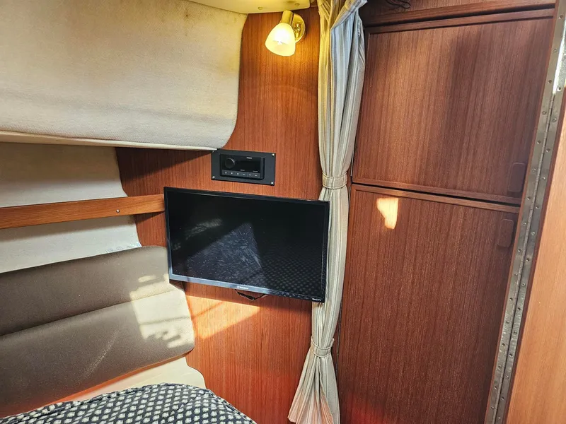 Slide: The Image of The interior of a 2014 Ranger Tugs 31-CB features a cozy bed, a TV, and wooden cabinetry. - 36