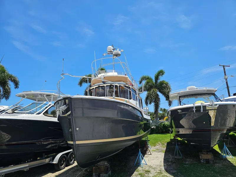 Slide: The Image of A 2014 Ranger Tugs 31-CB on a trailer between other boats, surrounded by palm trees. - 3